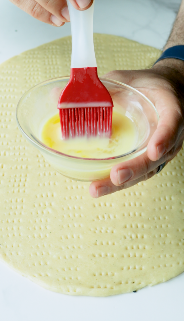 When ready to bake, preheat your oven to 350 degrees.
Flatten the dough to an inch thickness, use a fork to create holes all over the top, and brush it with an egg wash.